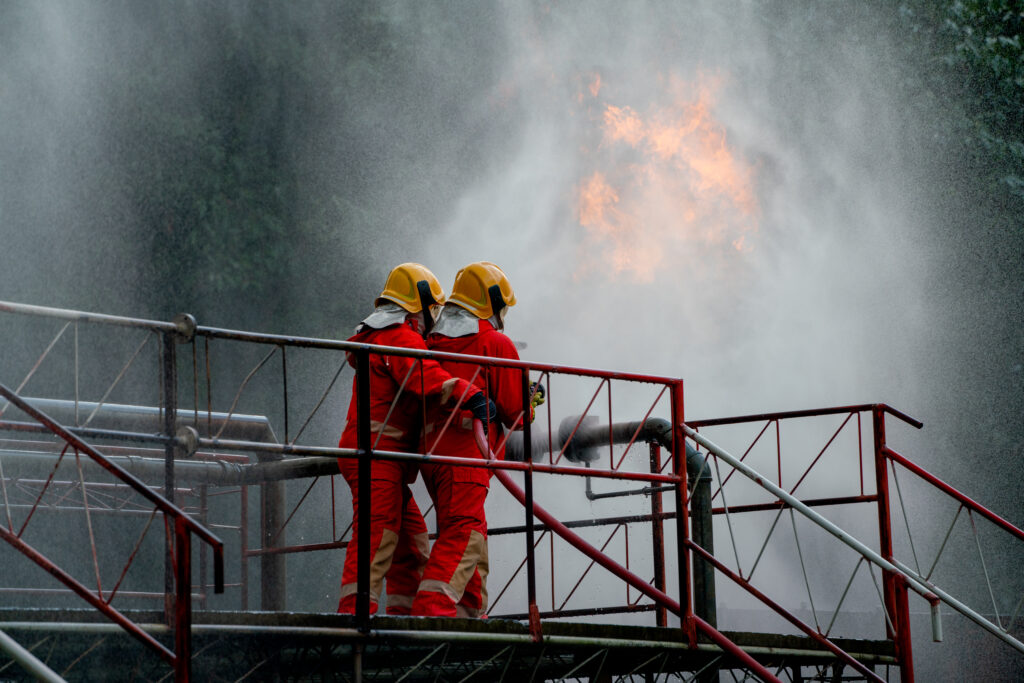Two firefighter try to extinguish or get rid of fire from gas pipe on top of building